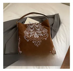 Close-up of ethnic embroidery and texture on a brown suede tote bag in a lifestyle setting