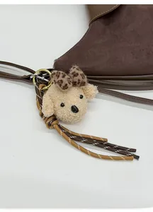 Detail of cute dog plush pendant with leopard bow and woven rope on tote bag