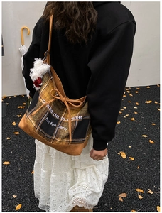 Detail of yellow checkered tote bag featuring plush puppy charm and side drawstring bow