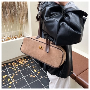 Brown suede shoulder bag with gold square lock shown on a model in urban style