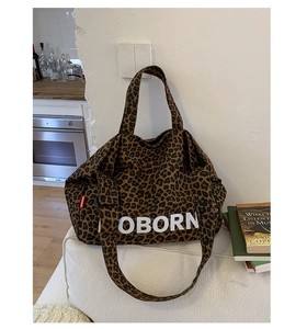 Detail of leopard print tote bag showing dual straps and white letter logo on canvas