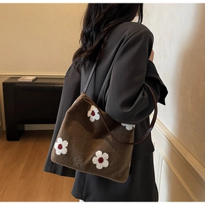 Détail du tissu en peluche marron et de la broderie florale du sac sous l'aisselle
