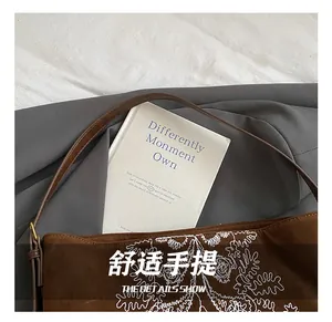 Close-up of ethnic embroidery detail on brown suede tote bag with vintage aesthetic