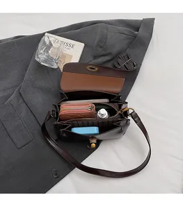 Détail de l'intérieur du sac en cuir marron avec plusieurs compartiments et fermoir rotatif