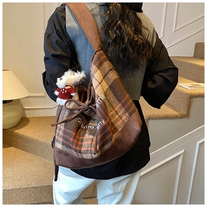 Detail of vintage plaid hobo bag featuring tweed texture and cute white puppy plush charm