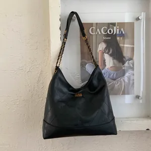 Nahaufnahme einer schwarzen Steppleder-Hobo-Tasche mit goldener Kette und Drehverschluss