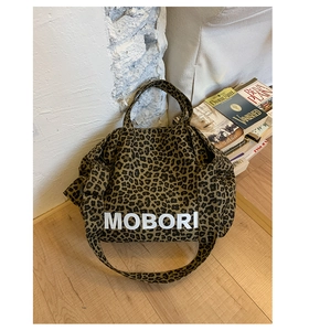 Detail view of leopard print canvas tote bag with Mobori text on a wooden floor