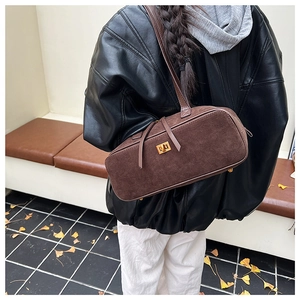 Close-up of the vintage brown suede baguette bag with a gold twist lock and leather straps