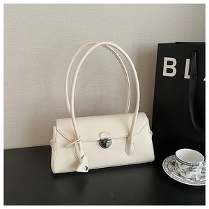Detailed macro of cream faux leather shoulder bag with silver shield buckle and heart charm
