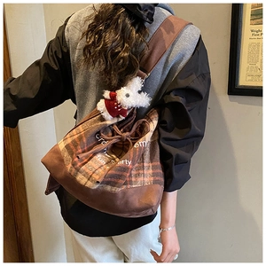 Detail of retro plaid bucket bag with drawstring closure and cute rabbit plush charm