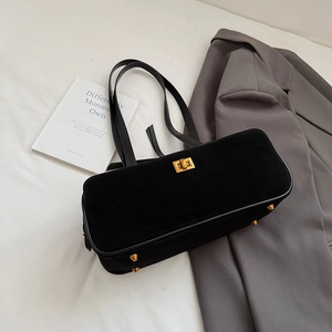 Close-up of black suede baguette bag with golden metal twist lock and protective feet