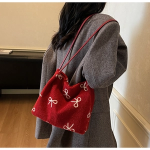 Détail du sac cabas en tricot rouge avec motif nœud blanc et bandoulière en cuir
