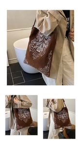 Detail view of ethnic embroidery on brown suede tote bag featuring white floral patterns