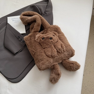 Braune Plüschtasche mit 3D-Bär-Design auf einem dunkelgrauen Sakko Hintergrund liegend
