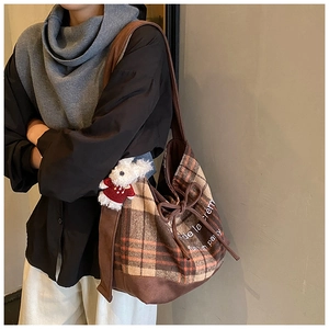 Detail of vintage brown plaid tote bag with drawstrings and a small rabbit plush charm