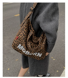 Detail of leopard print tote bag with wide shoulder strap and white logo lettering