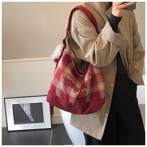Detailed view of red plaid canvas tote bag with script text and plush keychain accessory