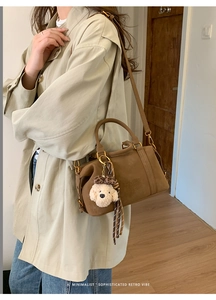 Close-up of brown retro crossbody bag with plush dog charm and leopard scarf detail