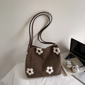 Détail d'un sac cabas en feutre marron avec broderie fleurie blanche et anses en cuir