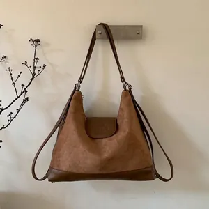 Detailed view of brown suede tote bag featuring embossed elephant logo and leather trim