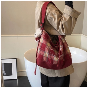Detailed side view of a vintage red checkered tote bag with plush charm and shoulder strap