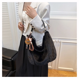 Détail du sac hobo en fausse fourrure noire avec sangle en cuir et breloque ours