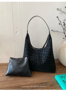 Détail du sac cabas léopard avec pochette en cuir sur une table en bois vintage