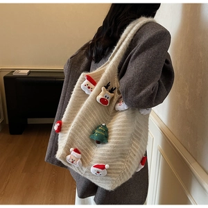 Detail of beige knit tote bag featuring plush 3D Christmas charms and festive embroidery