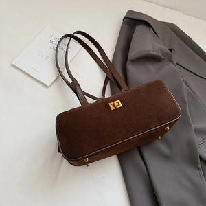 Detail view of brown suede baguette bag with golden twist lock and protective metal feet