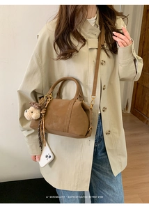 Brown Boston handbag detail featuring branded embossing, plush bear charm and silk scarf