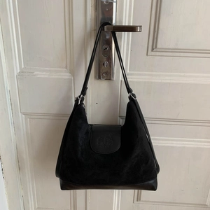 Detail of suede and smooth leather stitching on a black tote bag with embossed logo