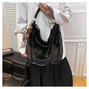 Dettaglio della borsa hobo in pelliccia nera con tracolla in pelle e ciondolo leopardato