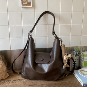 Detail of deep brown faux leather tote bag with flap closure and cute plush charm