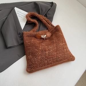 Detailed macro of caramel knit tote bag showing horn buckle and leather patch