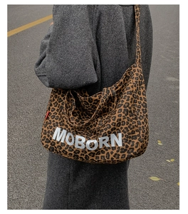 Detail of leopard print tote bag with white MOBORN lettering and wide shoulder strap