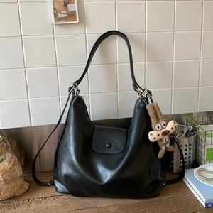Detail of black soft leather Hobo bag featuring a cute plush bunny charm on a wooden surface