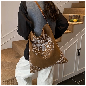 Detail of bohemian white embroidery on caramel brown faux suede tote bag