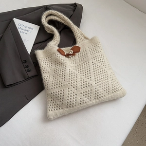 Detailed close-up of cream crochet tote bag featuring hollow knit patterns and leather toggle