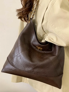 Retro tiefbraune Stepptasche mit goldener Kette getragen mit einem beigen Trenchcoat