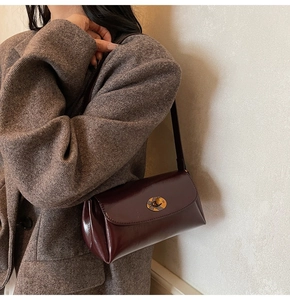 Détail du sac à bandoulière en cuir bordeaux avec fermoir métallique et insert à carreaux