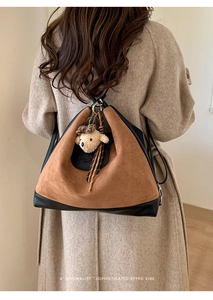Detail of retro brown suede tote bag with plush puppy charm on a wool coat