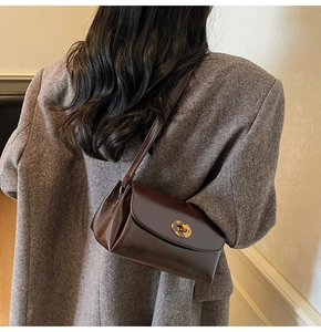 Détail d'un sac à bandoulière marron foncé rétro avec fermoir rotatif ovale doré élégant