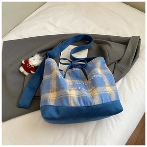 Close-up of blue plaid canvas hobo bag with drawstring bow and cute bear keychain