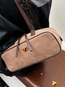 Brown suede baguette bag with leather strap and gold clasp on black leather outfit