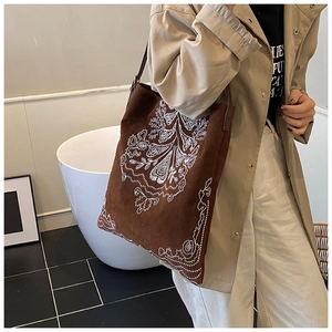Detail of ethnic suede tote bag with white bohemian floral embroidery and shoulder strap