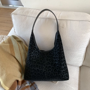 Détail de la texture du sac cabas léopard sur un canapé avec une écharpe élégante