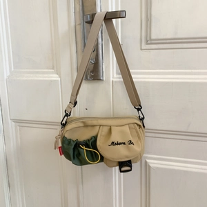 Detailansicht der beigen Nylon-Umhängetasche mit grüner Kordelzugtasche und breitem Gurt