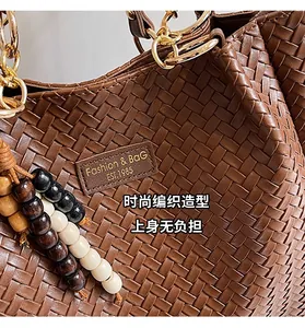 Gros plan du sac cabas tressé caramel avec anneaux dorés et pendentif en perles