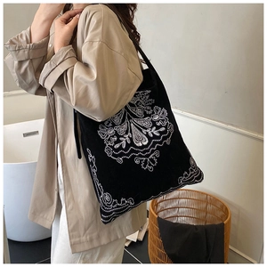 Close-up of ethnic style embroidery on a large black suede tote bag for women