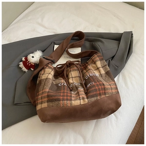 Detail of vintage plaid tote bag with drawstring closure and stylish wide fabric strap